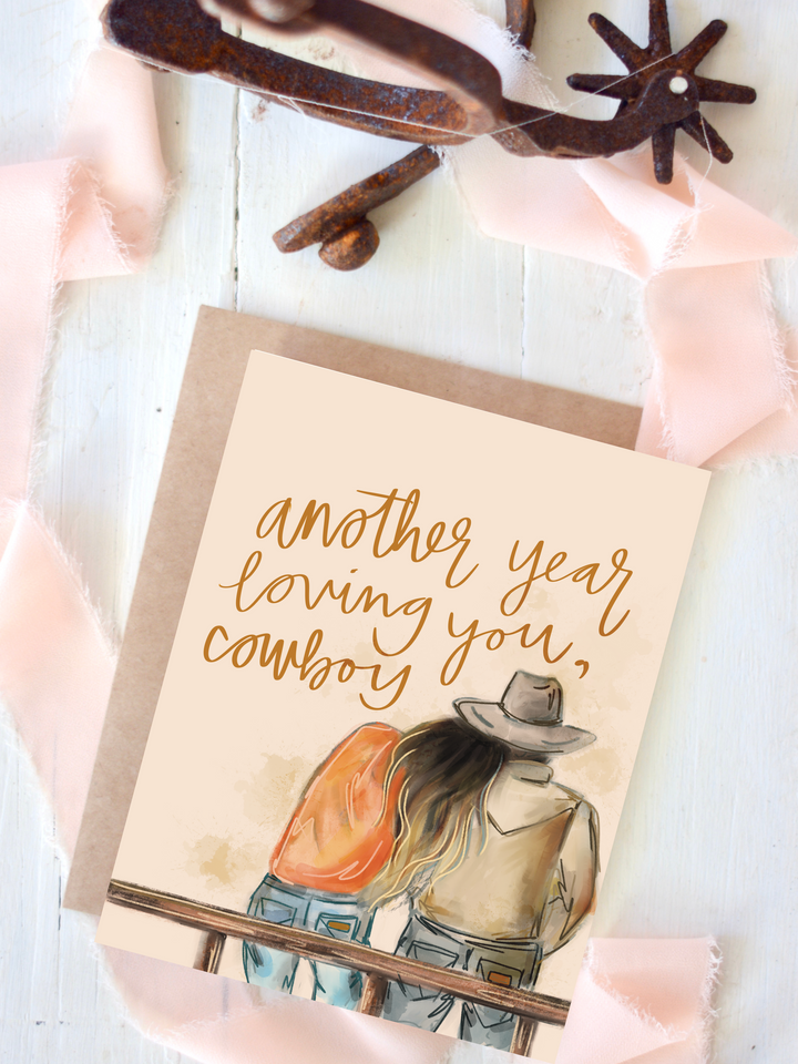 Another Year Loving You card, featuring a cowboy and cowgirl sitting together on a fence, seen from behind