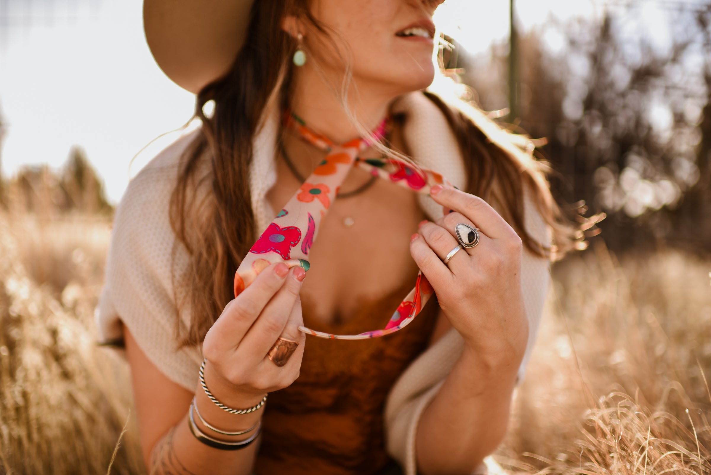 Woman holding a colorful twilly scarf in a sunlit field