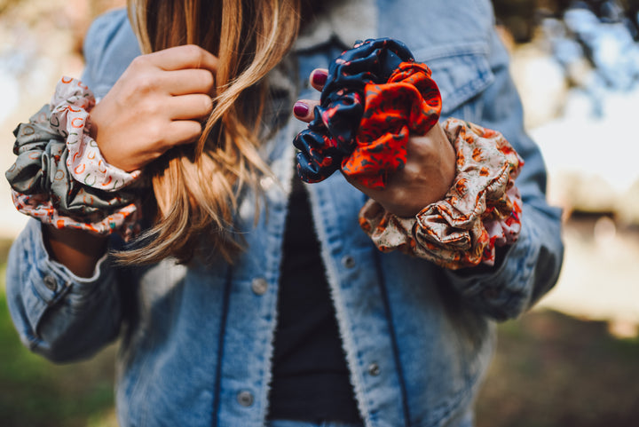 Person holding colorful scrunchies with a blurred natural background